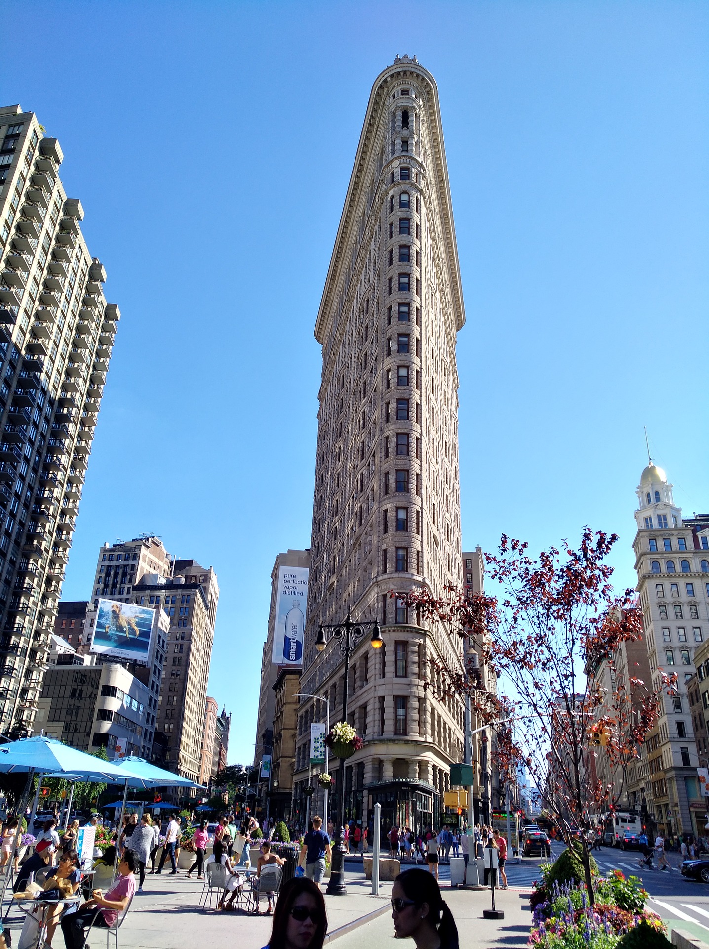 a group of people walking in front of a tall building with Flatiron Building in the background