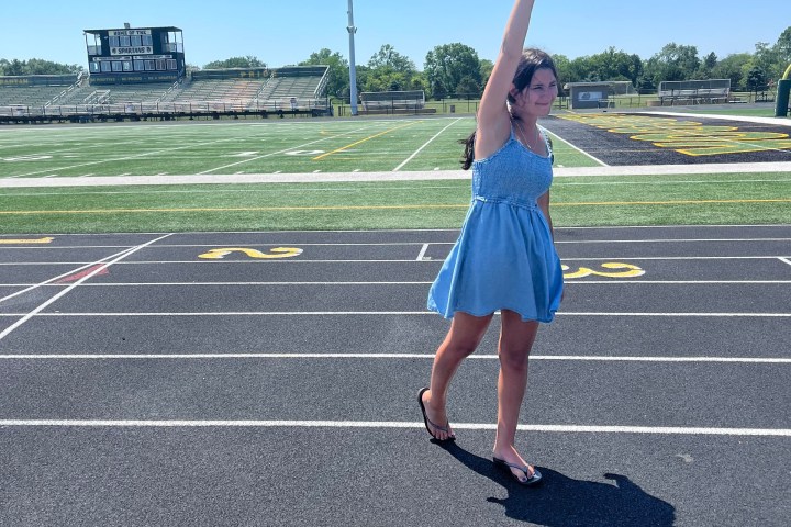 a person holding a kite while standing in a parking lot