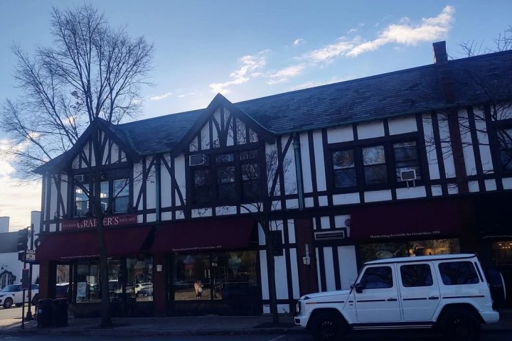 Tudor-style building with a white SUV parked in front.