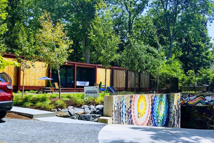 Artistic building with wooden slats, vibrant mural, surrounded by trees.