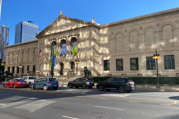 a car driving down a street in front of Art Institute of Chicago